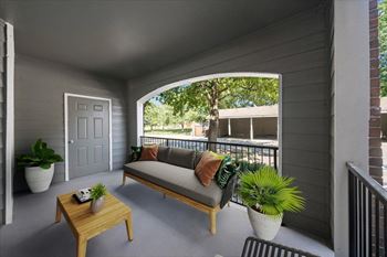 A balcony with a sofa, table, and potted plants. at Somerset Oaks Apartment Homes, Olathe, KS